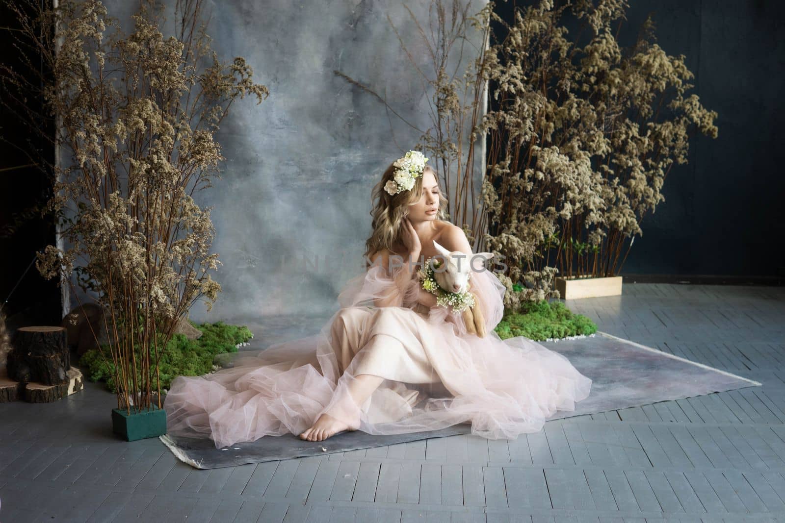 A young blonde woman in an airy pink dress with a white kid. Spring portrait of a woman