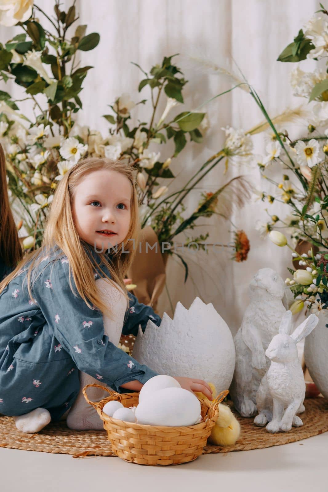 Two girls in a beautiful Easter photo zone with flowers, eggs, chickens and Easter bunnies. Happy Easter holiday. by Annu1tochka