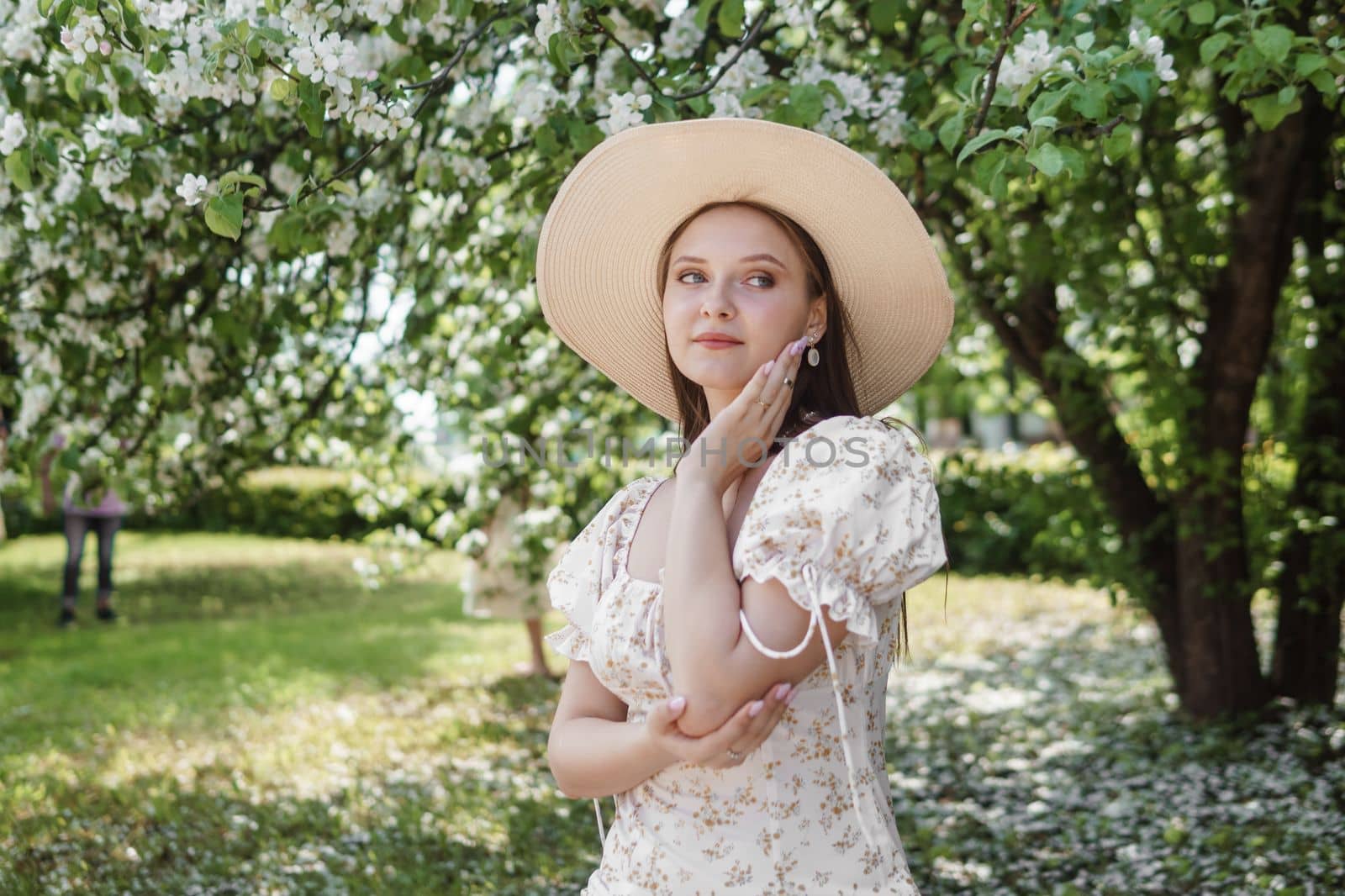 An attractive long-haired woman walks in the spring in the park of blooming apple trees. Spring portrait of a woman