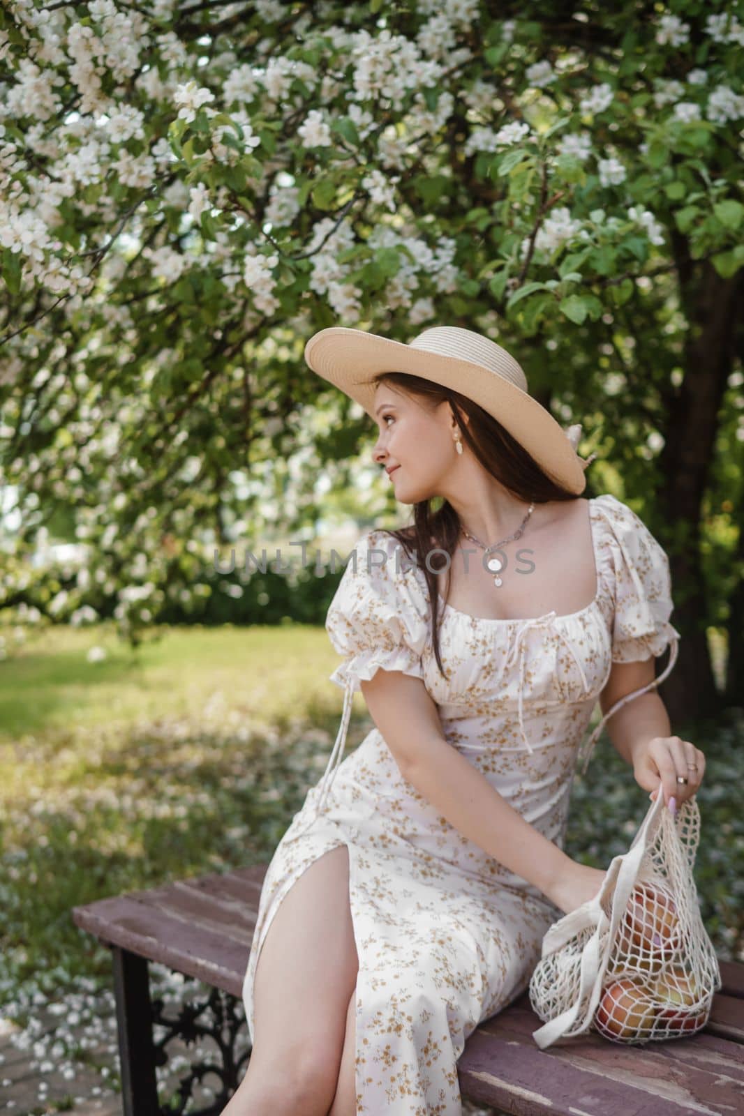 An attractive long-haired woman walks in the spring in the park of blooming apple trees. Spring portrait of a woman