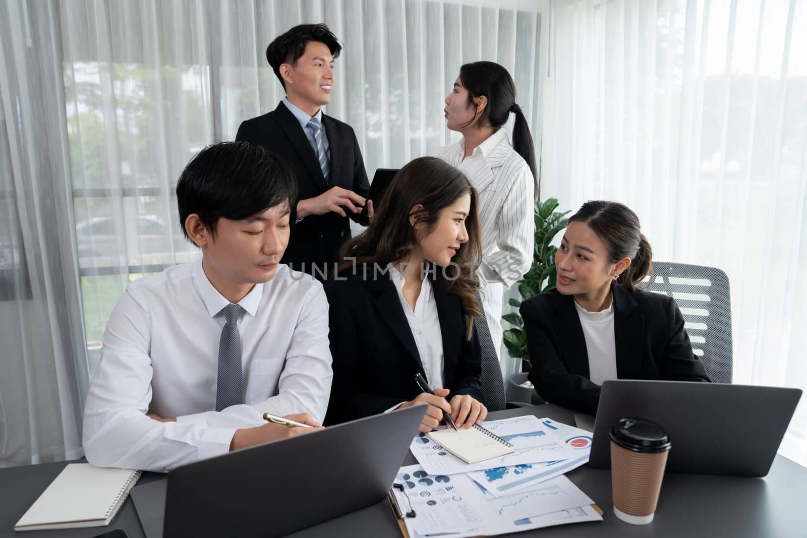 Harmony in office concept as business people analyzing dashboard paper together in workplace. Young colleagues give ideas at manager desk for discussion or strategy planning about project.