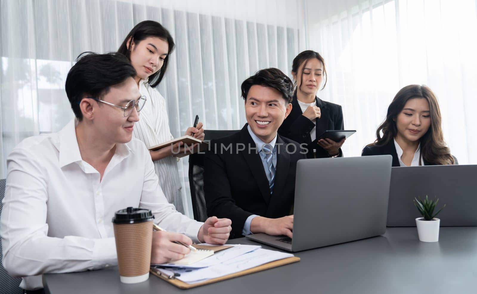 Harmony in office concept as business people analyzing dashboard paper together in workplace. Young colleagues give ideas at manager desk for discussion or strategy planning about project.