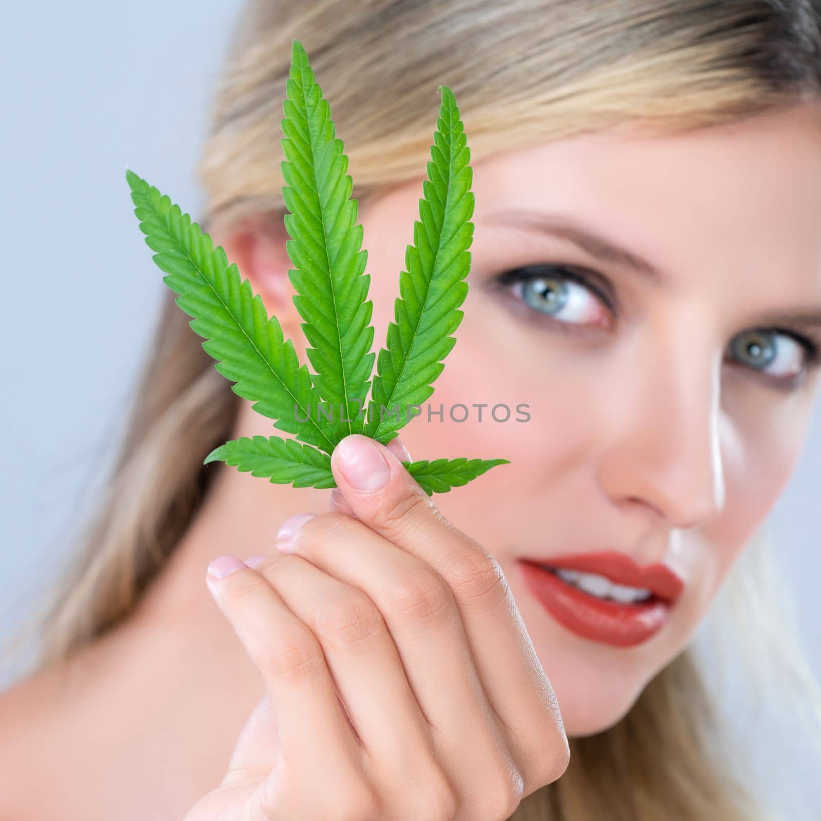 Closeup alluring woman portrait hold green leaf as cannabis beauty concept. by biancoblue