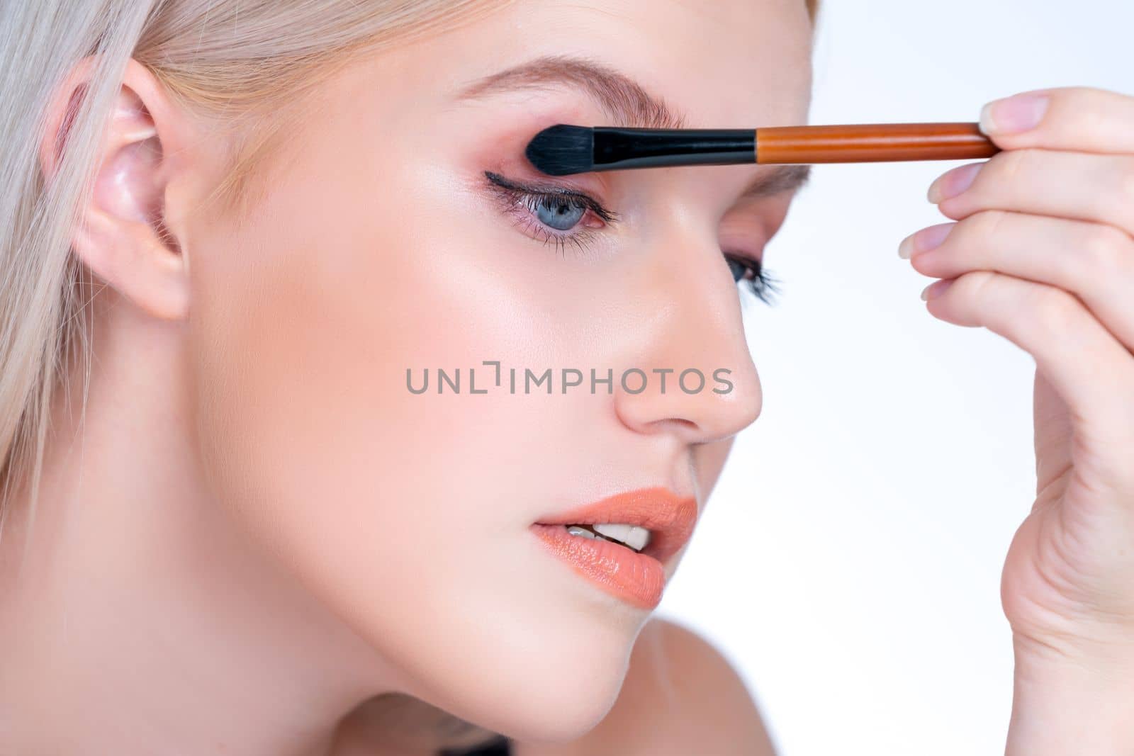 Closeup beautiful personable girl with flawless applying eye shadow makeup. by biancoblue