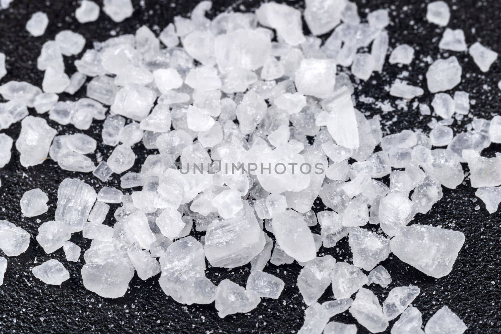 Sea salt on a black background close up macro. Sea salt granules of various sizes