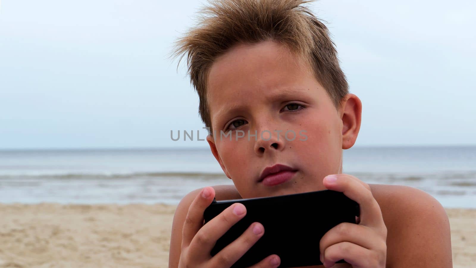 Cute boy on the beach with an electronic tablet close-up. by gelog67