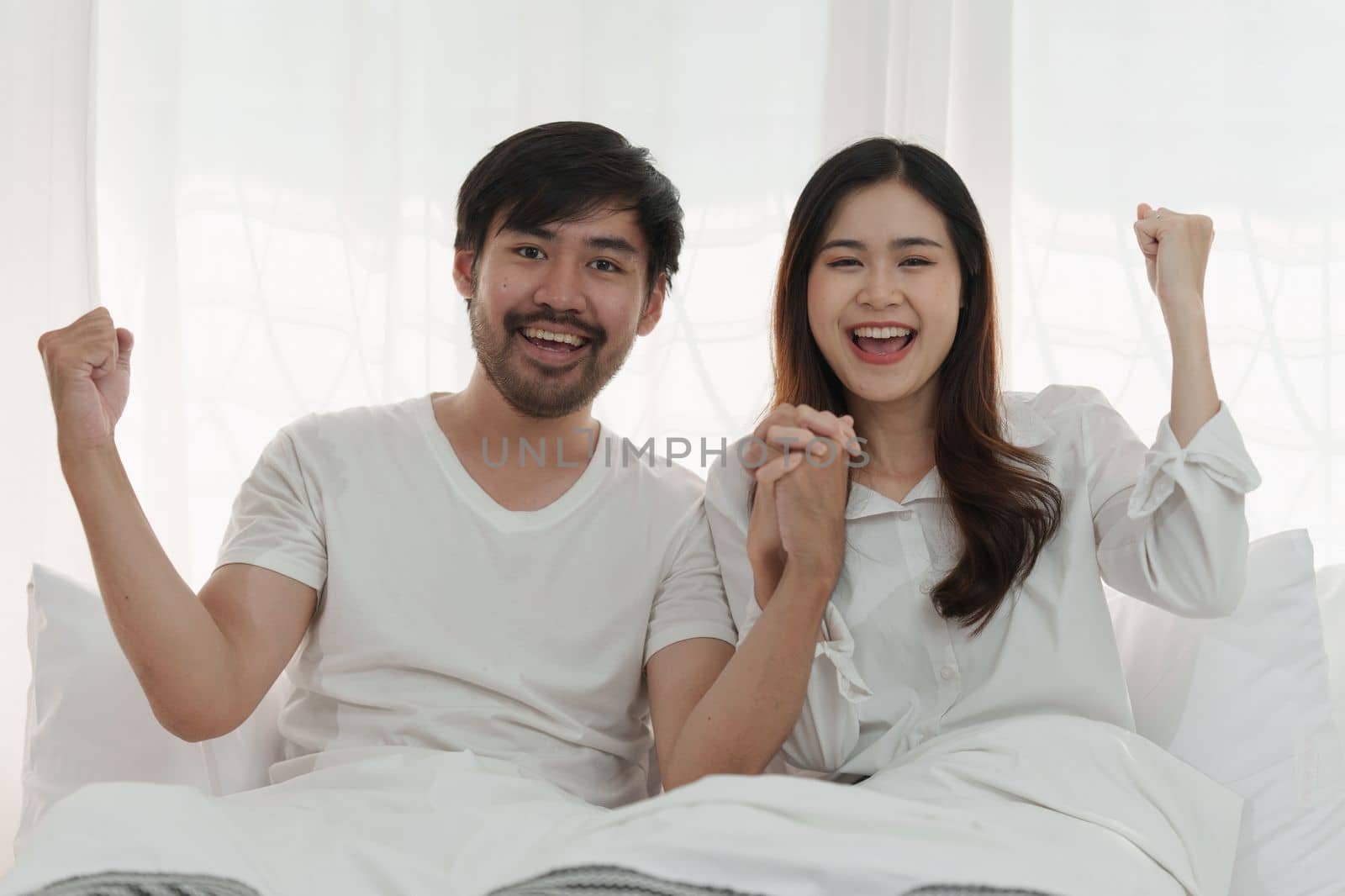 Beautiful asian couple in love and smiling sitting on bed. Romantic moment, relationships, family concept