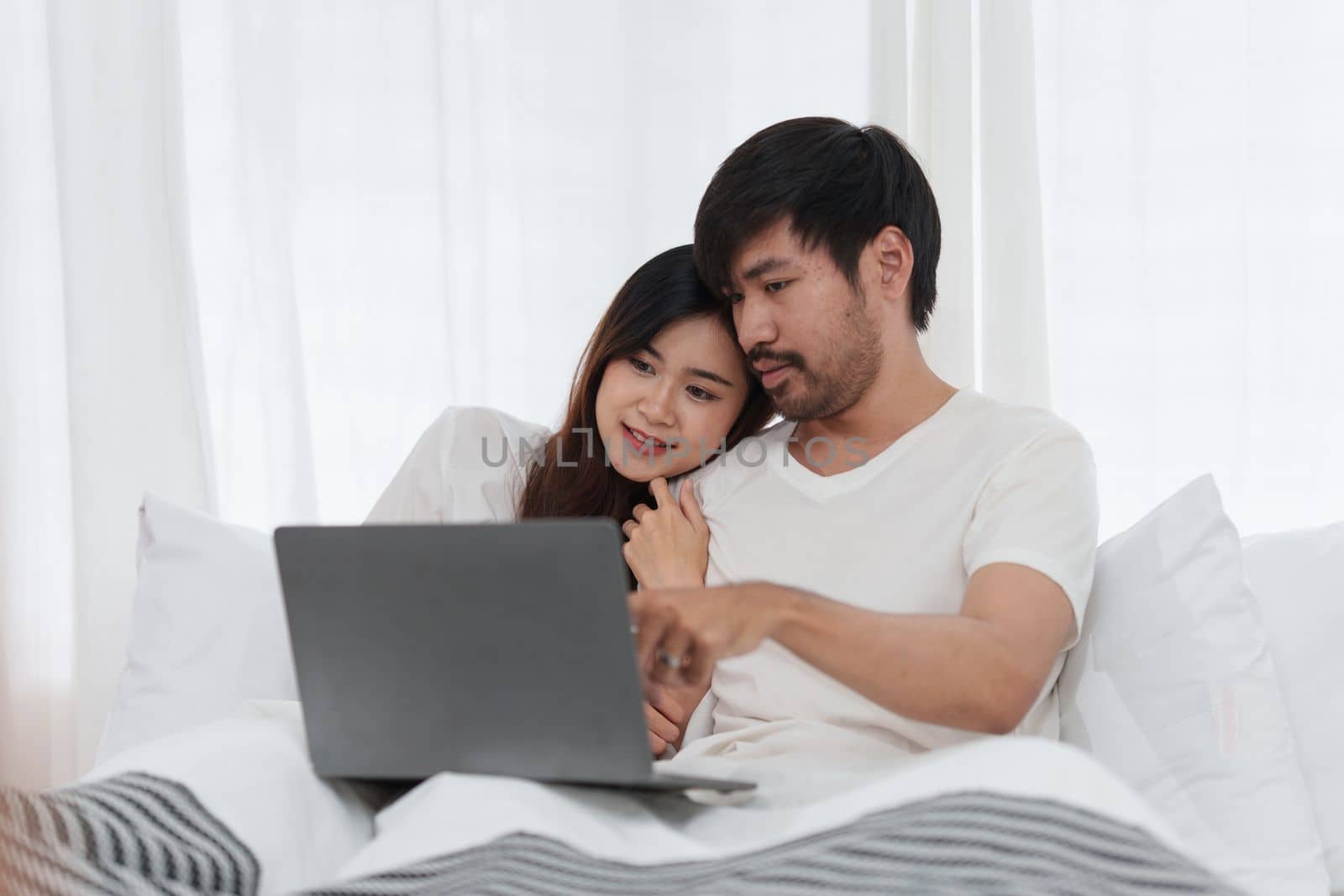 Beautiful asian couple in love and smiling sitting on bed. Romantic moment, relationships, family concept