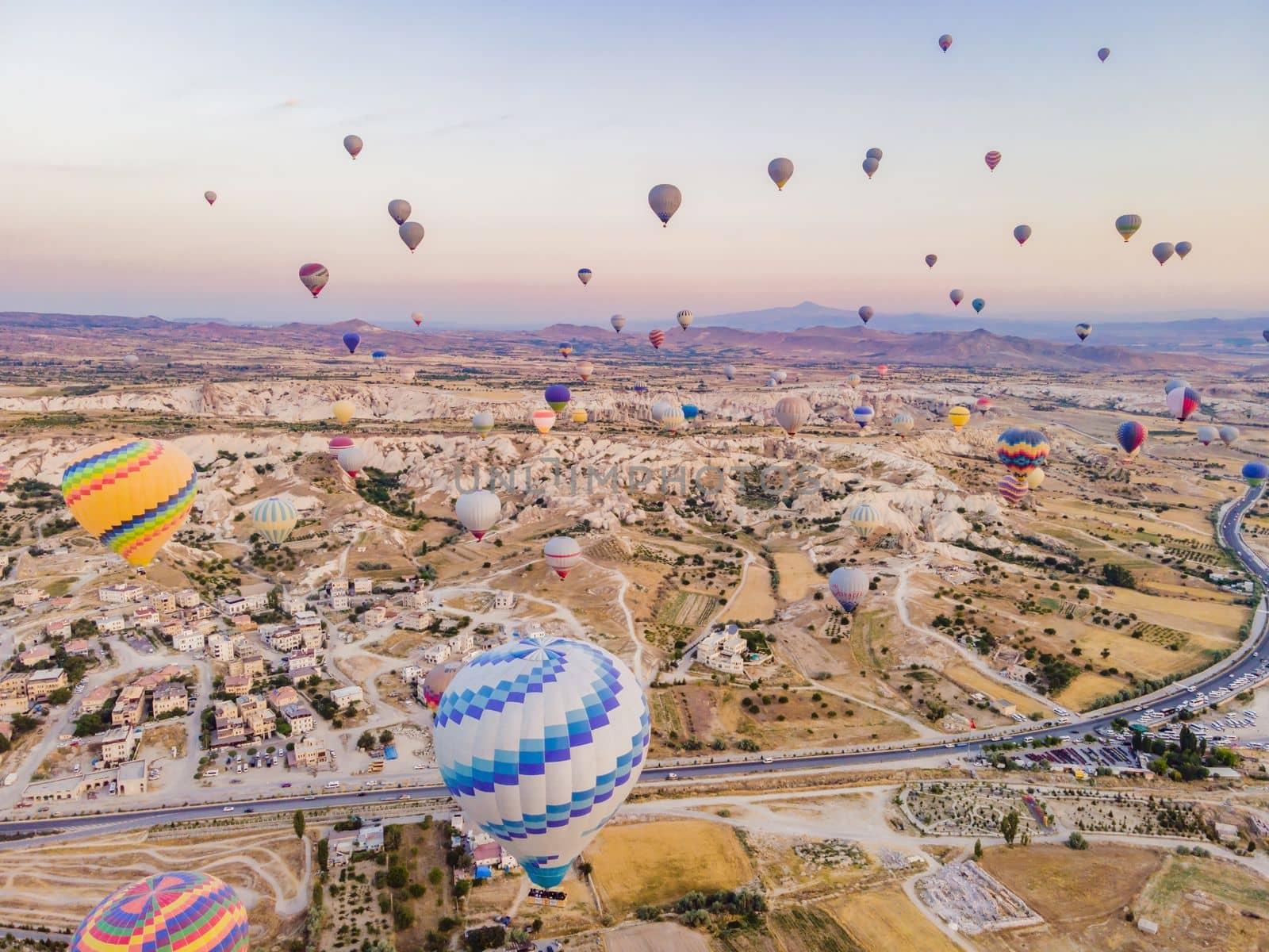 Colorful hot air balloons flying over at fairy chimneys valley in Nevsehir, Goreme, Cappadocia Turkey. Spectacular panoramic drone view of the underground city and ballooning tourism. High quality by galitskaya