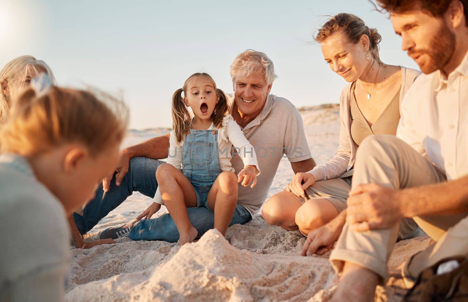 Parents building a sandcastle with their children. Family enjoying a beach holiday together. Little girls playing with their family on the beach. Carefree family bonding during vacation together.