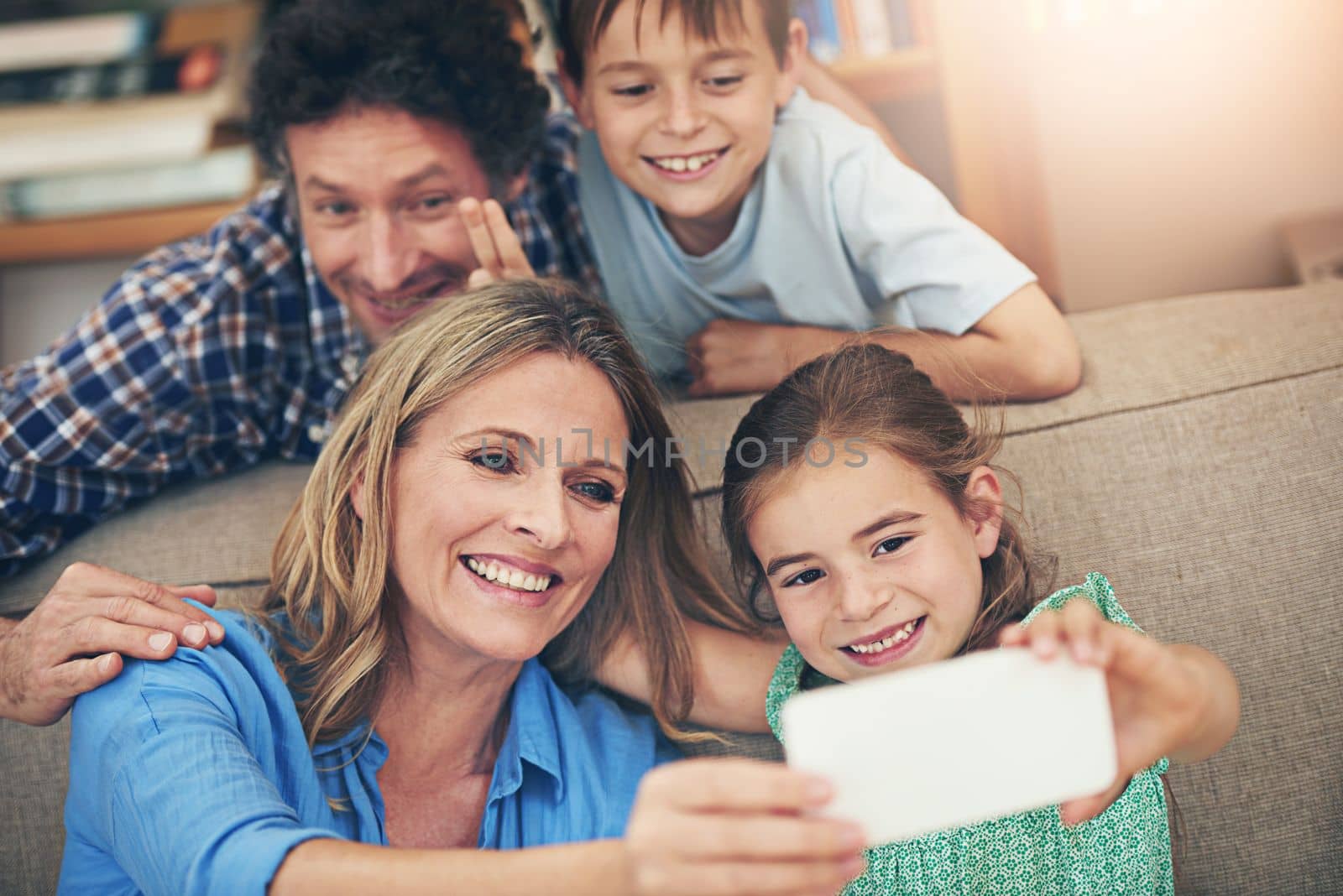 Family time is selfie time. a happy family taking a selfie together on a mobile phone at home. by YuriArcurs