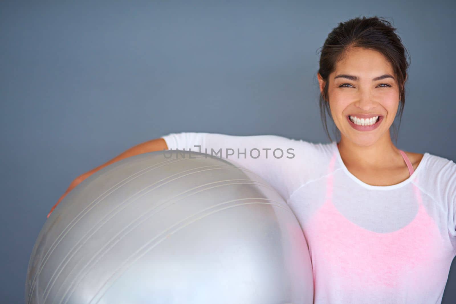 Everyday is a good day to workout. a sporty young woman holding a pilates ball against a grey background. by YuriArcurs