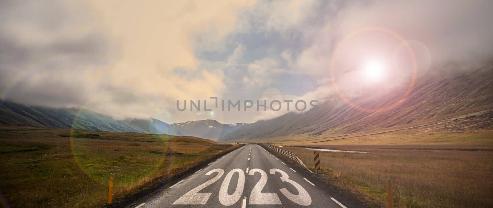The word 2023 written on highway road in the middle of empty asphalt road at golden sunset and beautiful blue sky. Iceland. High-quality photo