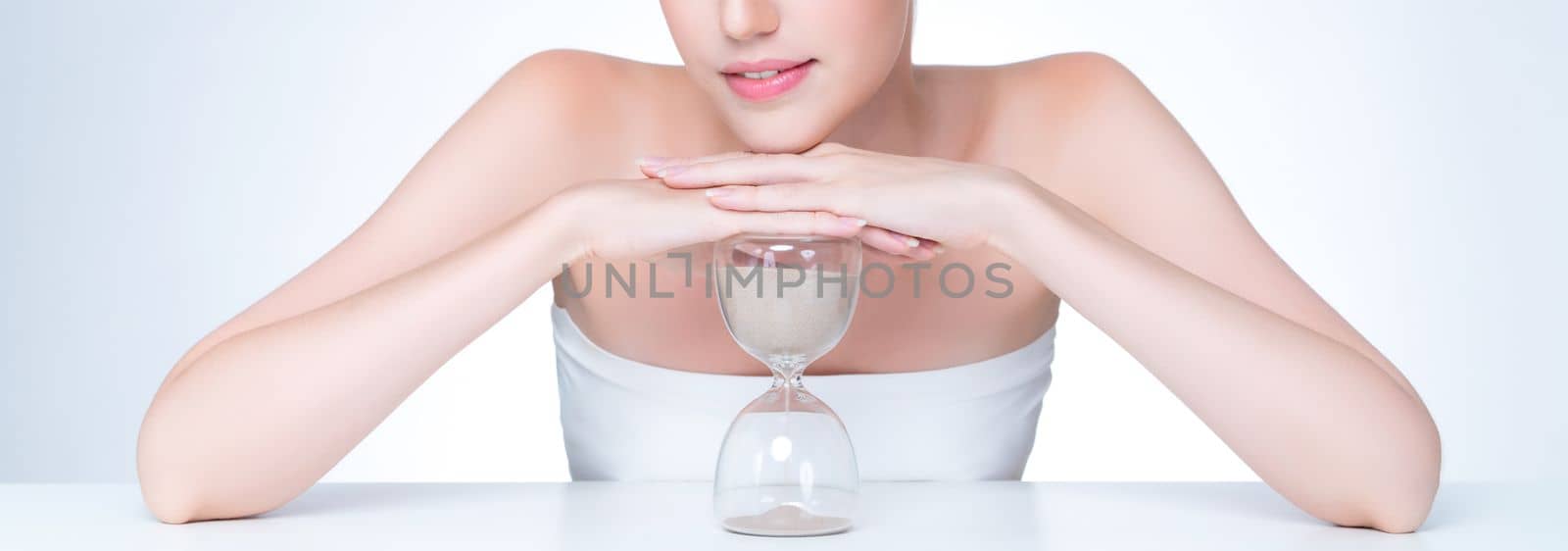 Closeup personable beautiful woman with hourglass as anti-aging skincare concept by biancoblue