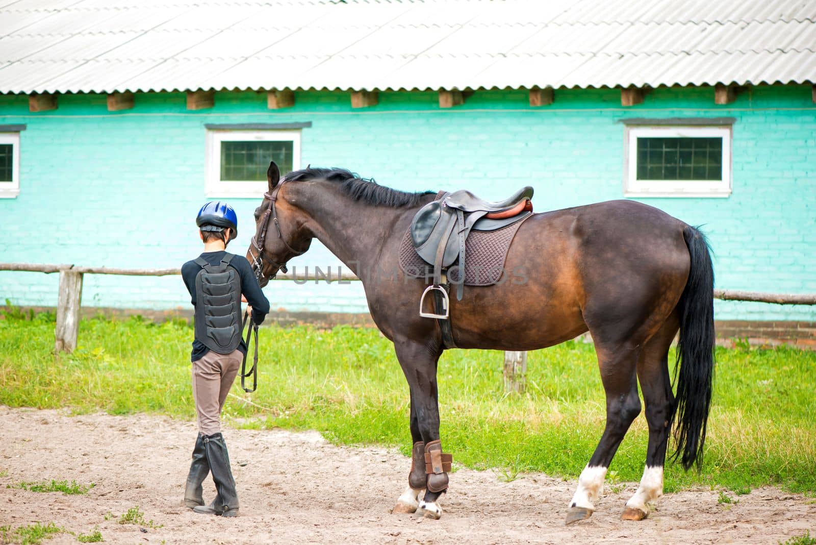 Horseback riding. The boy leads the horse by aprilphoto