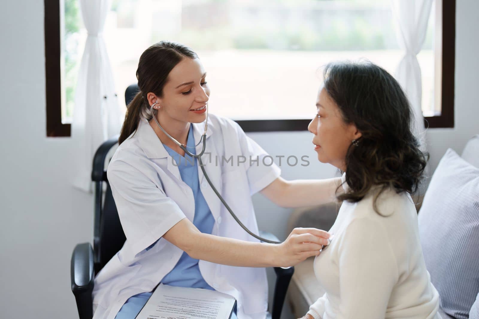 Portrait of a female doctor using a stethoscope to check the pulse of an elderly patient