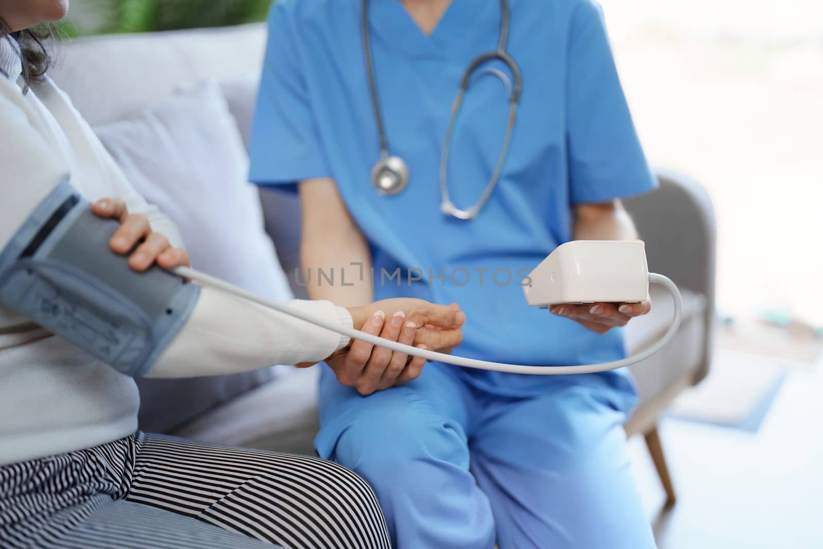 Portrait of female doctor measuring patient's blood pressure before treatment