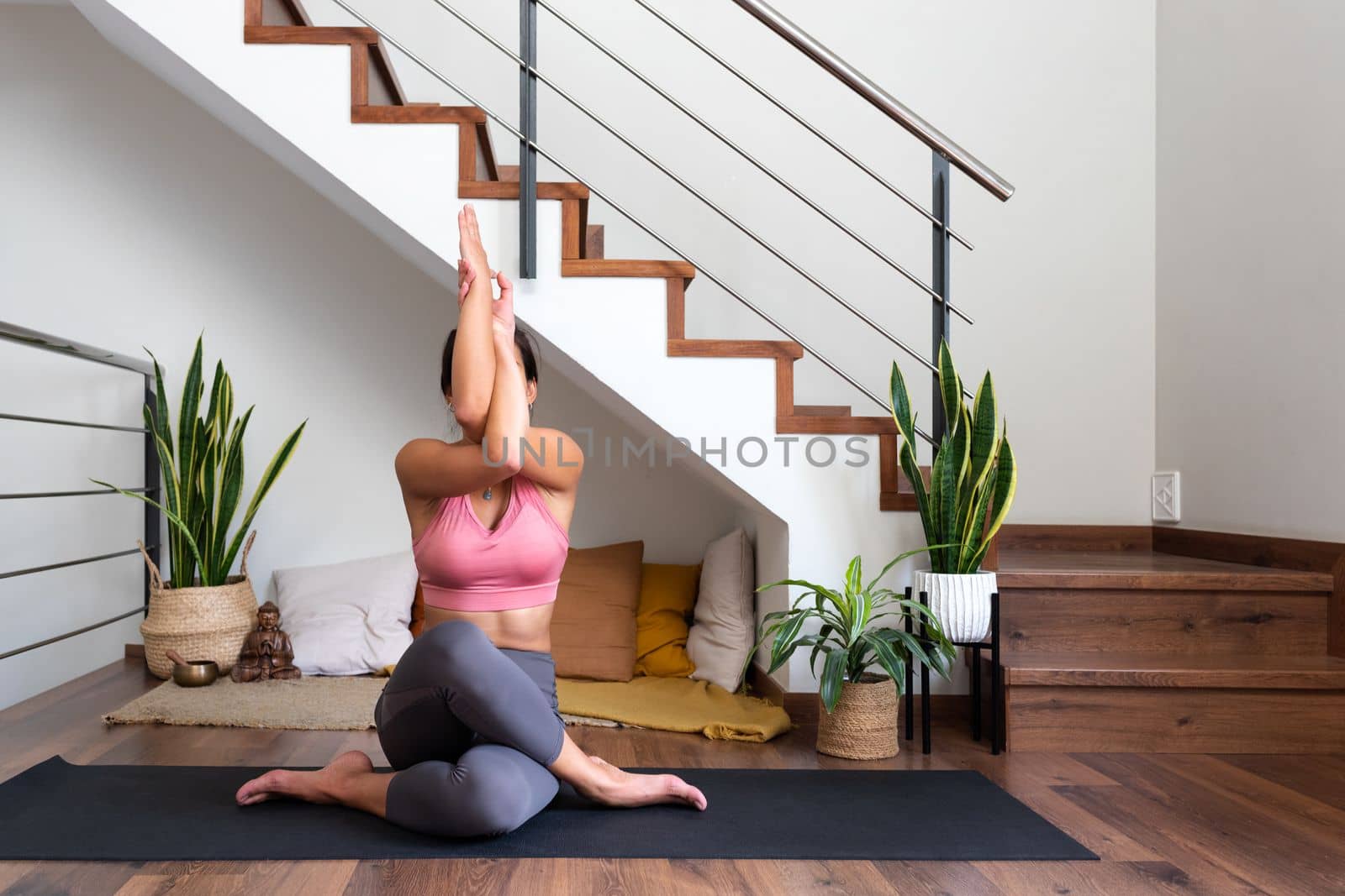 Young woman doing gomukhasana with garudasana arms. Home yoga practice in living room.Copy space. Healthy lifestyle and spirituality concept.