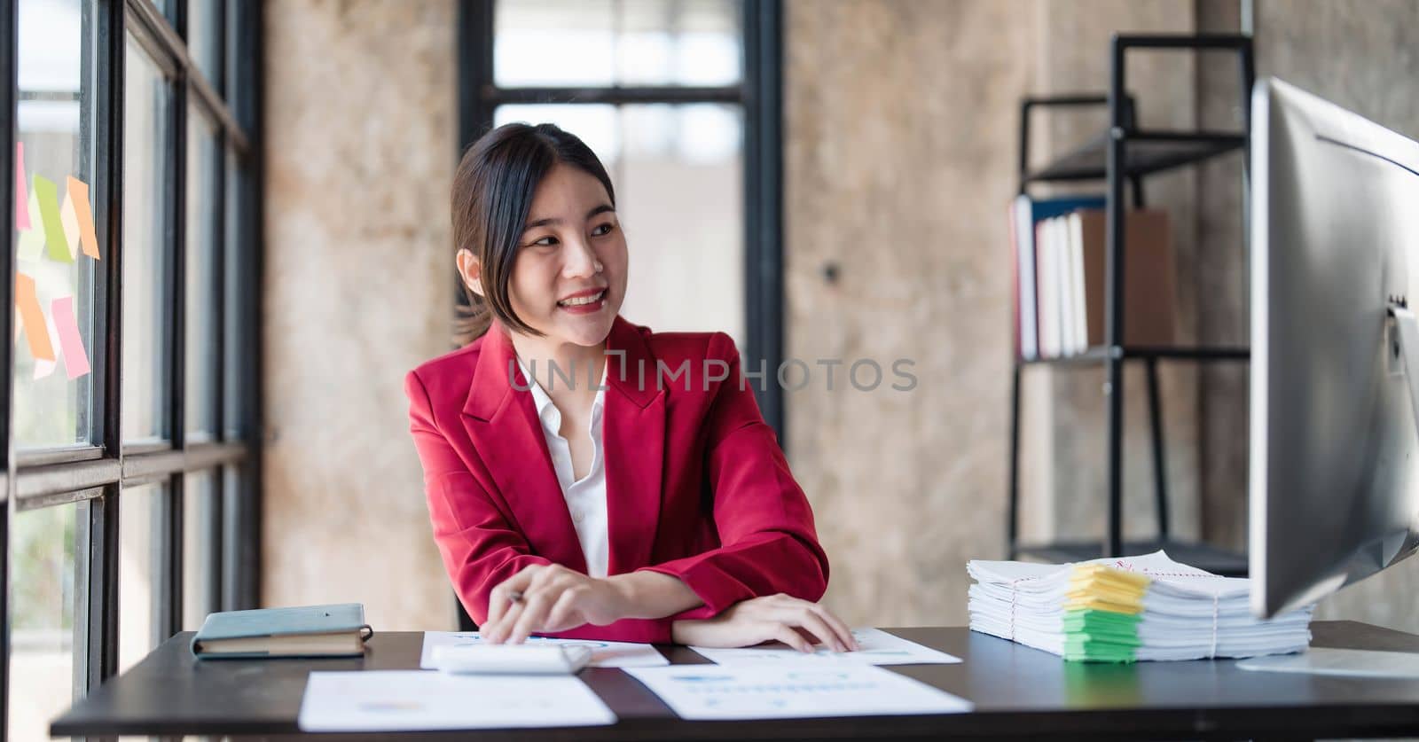 Portrait of smiling Asian businesswoman enjoying her work on her laptop at the office. by wichayada