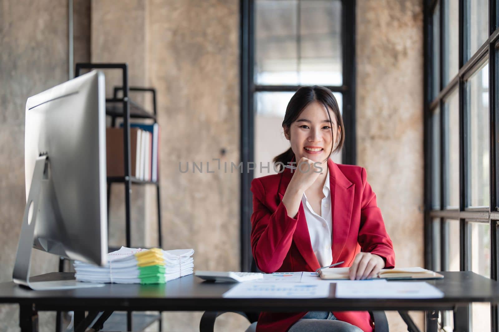Portrait of smiling Asian businesswoman enjoying her work on her laptop at the office. by wichayada