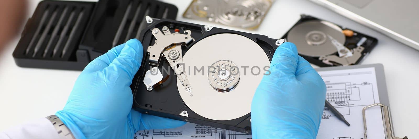 Technician repairs computer hard drive from motherboard by kuprevich