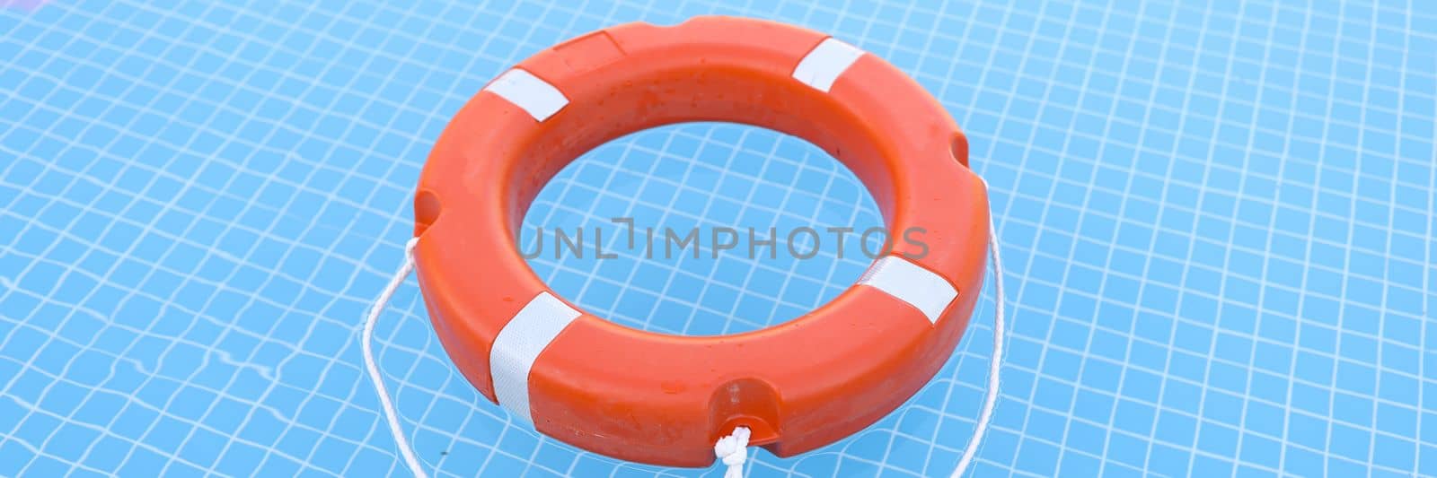 Lifebuoy on blue water with sun glare closeup by kuprevich