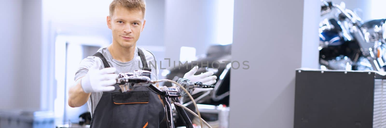 Auto mechanic checks technical condition of motorcycle in workshop. Vehicle service station services concept