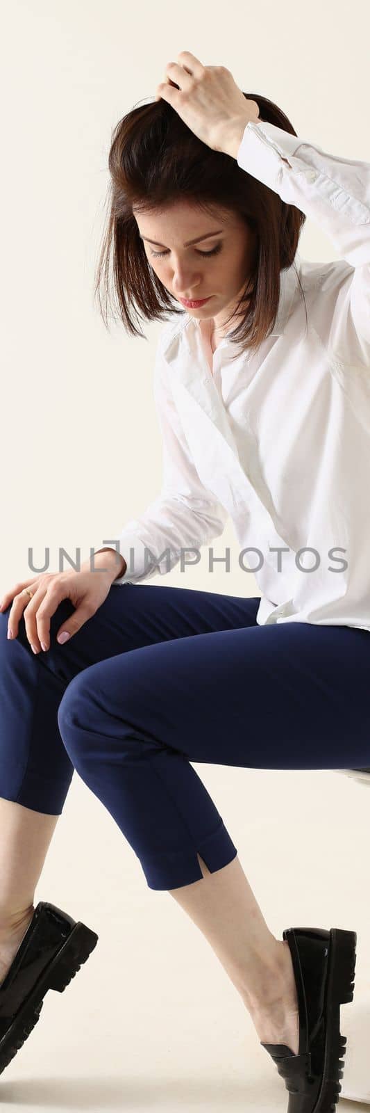 Woman in bad mood, bored and sad, sits on chair and puts hands on head. Woman in depression concept