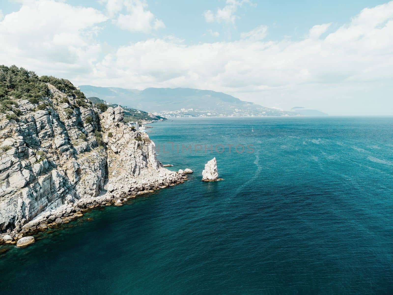 aerial photo of rock Parus Sail and Ayu-Dag Bear Mountain and near Gaspra, Yalta, Crimea at bright sunny day over the Black sea. Rock Parus in Gaspra near Swallow's nest in Crimea. by panophotograph