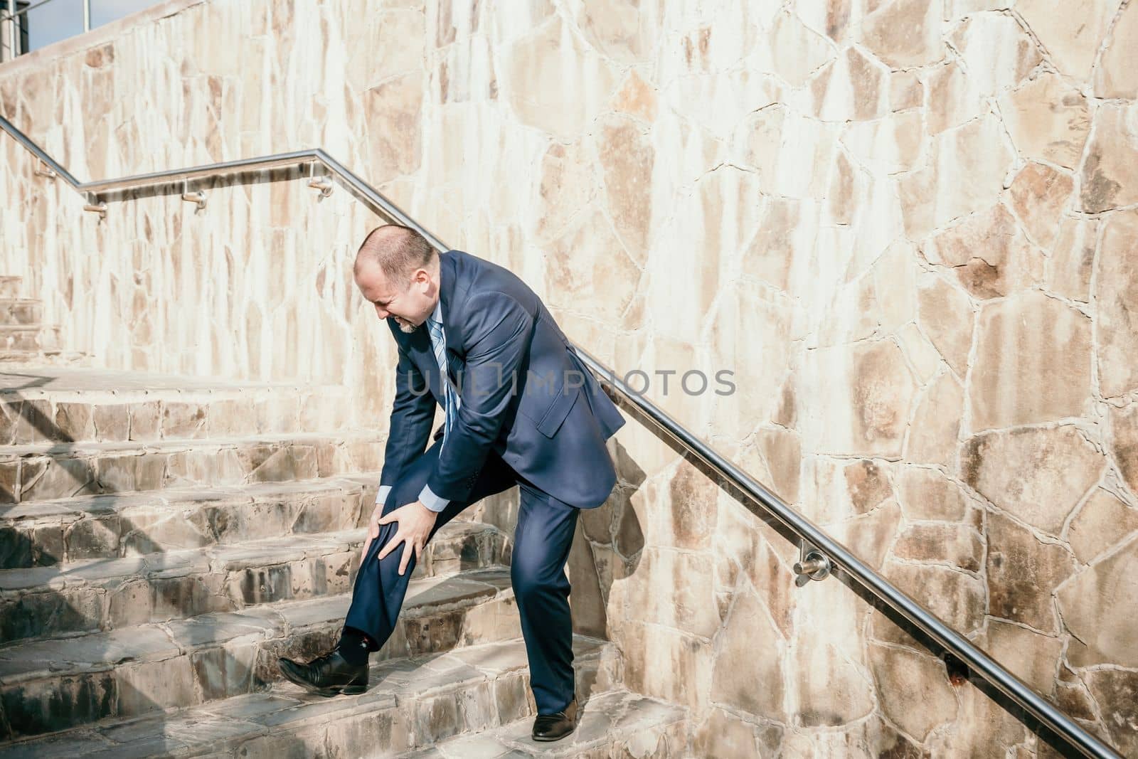 Portrait of a senior professional man in a suit with various problems. A middle-aged businessman with a briefcase descends the stairs.
