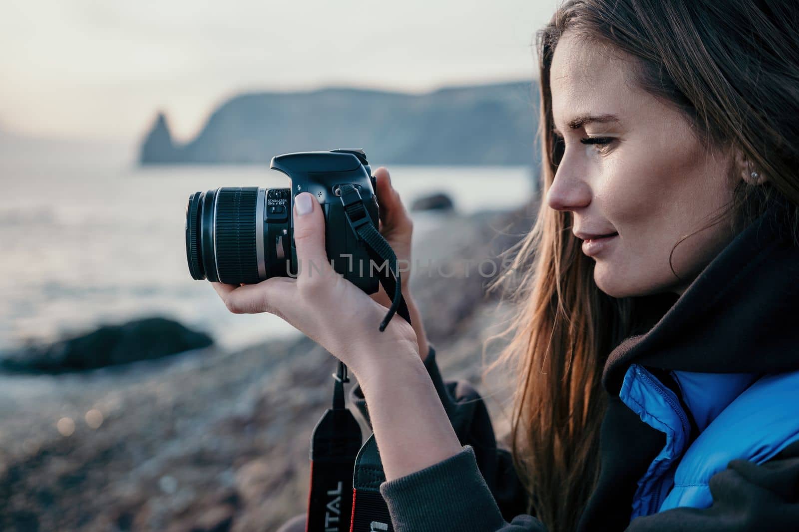 Woman travel sea. Happy tourist taking picture outdoors for memories. Woman traveler looks at the edge of the cliff on the sea bay of mountains, sharing travel adventure journey.