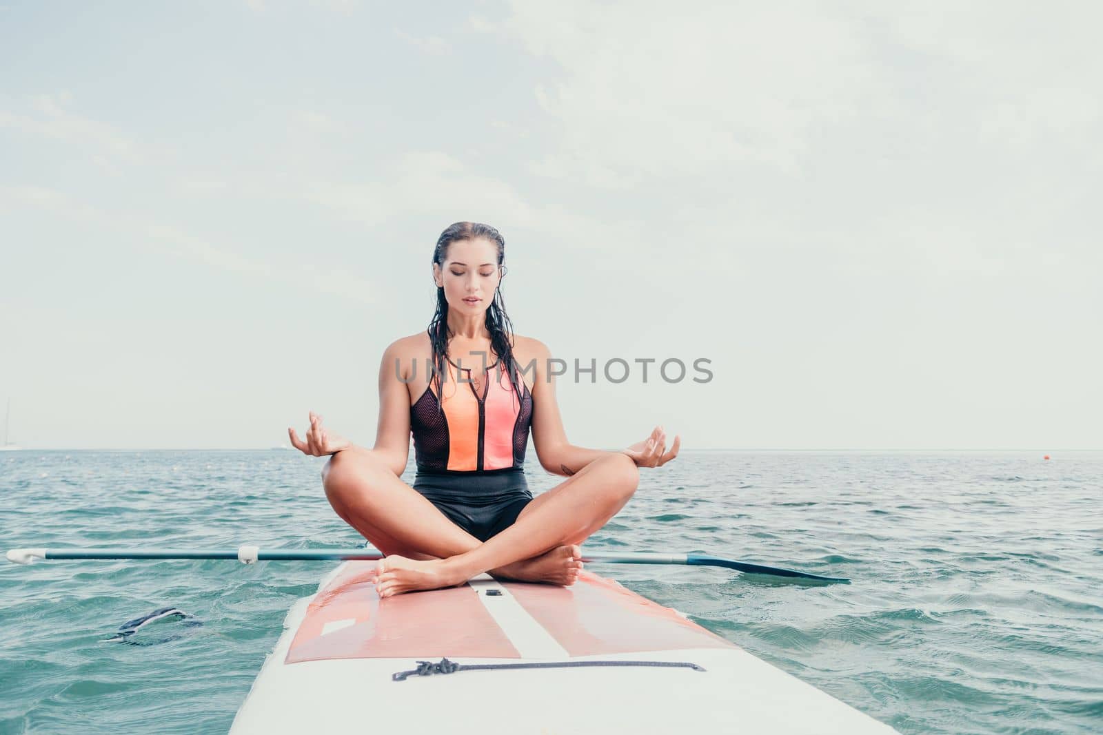 Woman sup yoga. Happy young sporty woman practising yoga pilates on paddle sup surfboard. Female stretching doing workout on sea water. Modern individual female outdoor summer sport activity