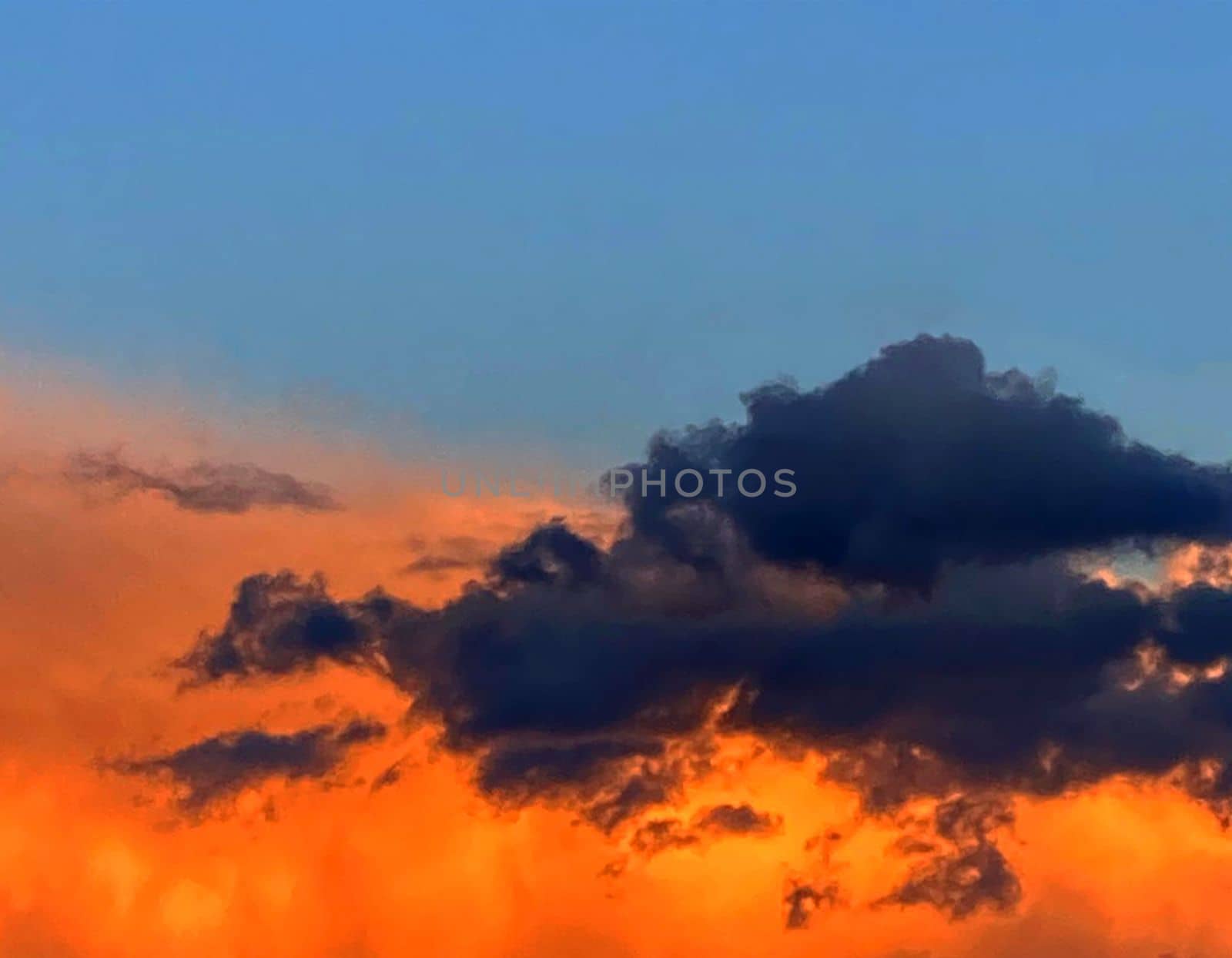Anxious sunset. Gray and orange clouds in blue sky. by Margo