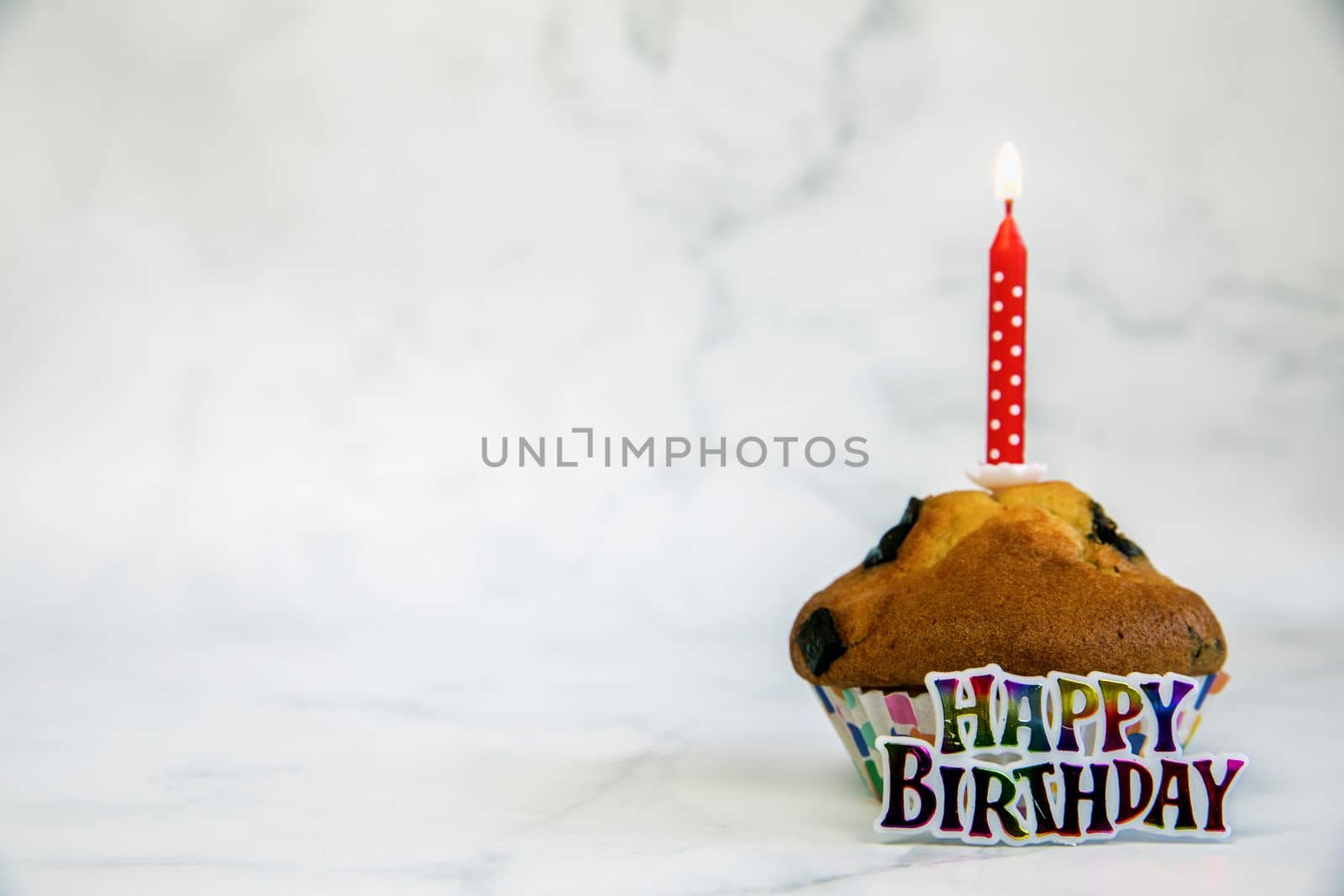 Birthday cupcake with and one red birthday cake candle on a white background with copyspace to side, Happy Birthday, party concept close up