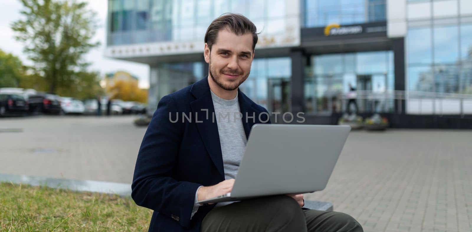 young charismatic successful businessman working on laptop outside.