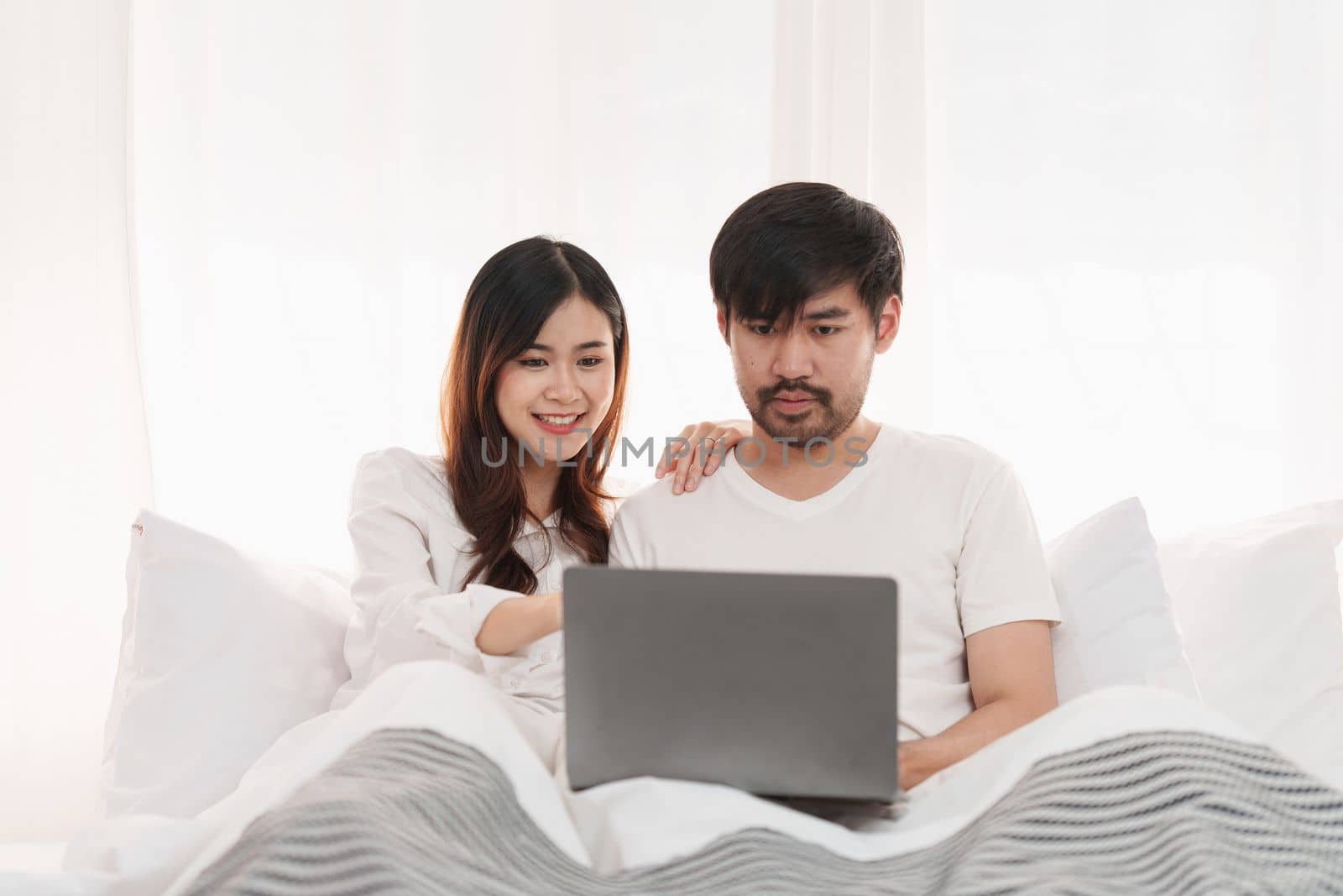 Beautiful asian couple in love and smiling sitting on bed. Romantic moment, relationships, family concept