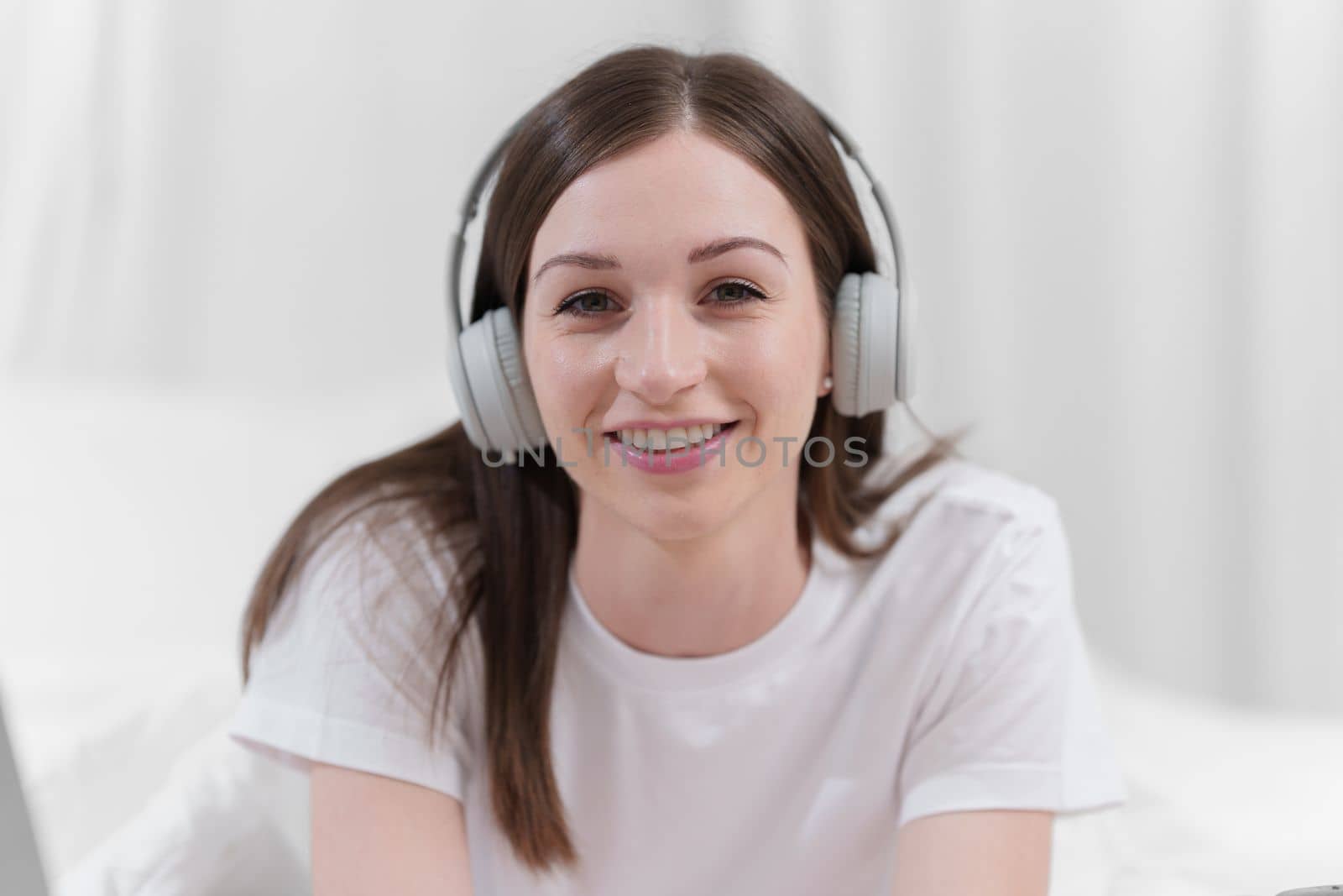 Image of beautiful young woman with headphone resting in bed at bedroom. Lifestyle at home concept