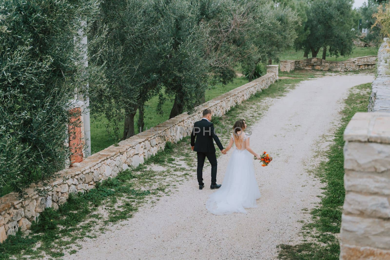 Happy stylish smiling couple walking in Tuscany, Italy on their wedding day. The bride and groom walk down the street by the hands. A stylish young couple walks. Husband and wife communicate nicely. Lovers run through the streets of the city.