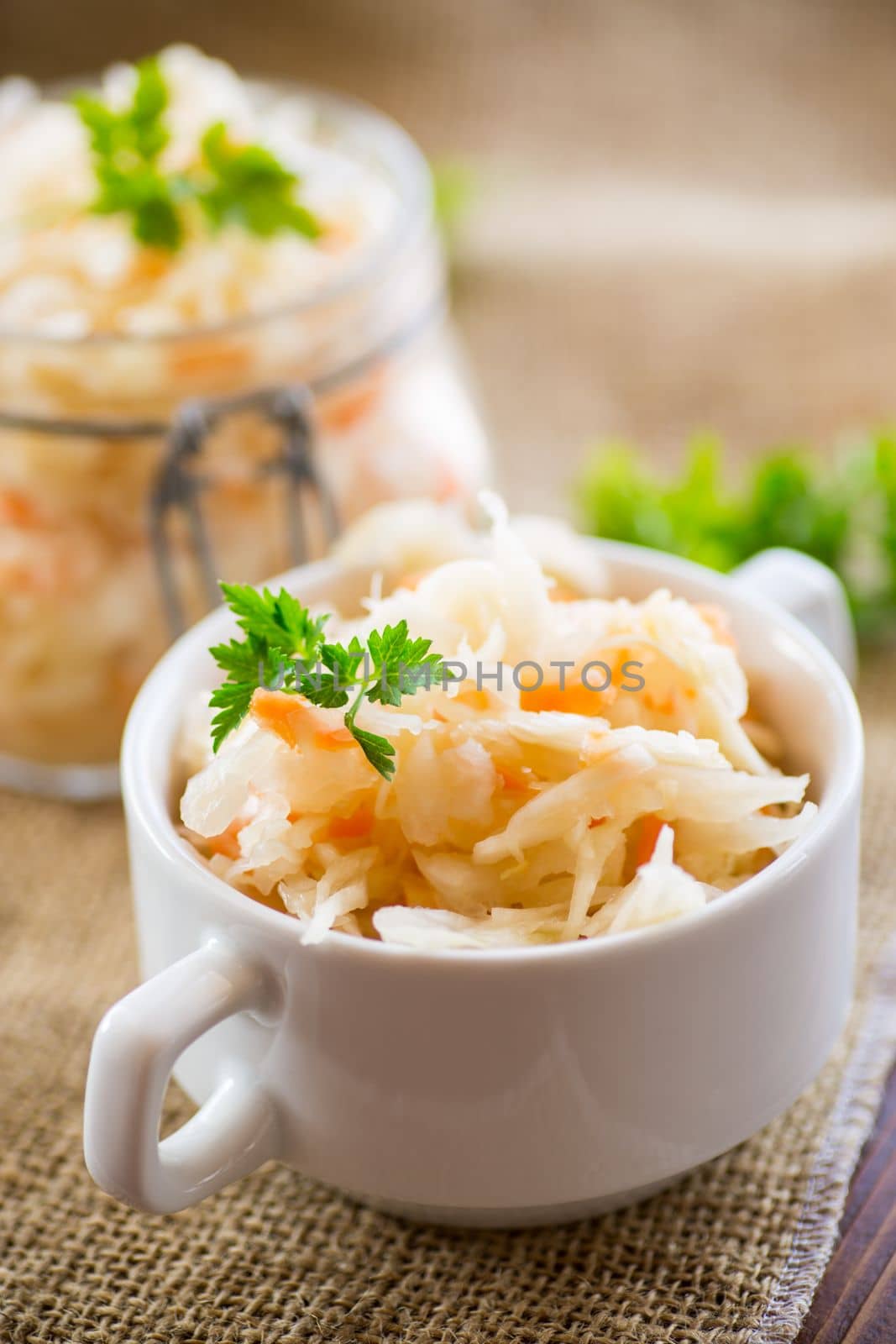 Sauerkraut with carrots and spices in a bowl on a wooden table.