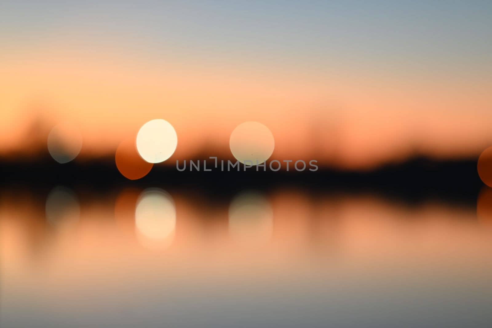 Evening mood besides a river against a container port and a beautyful blurry sunset