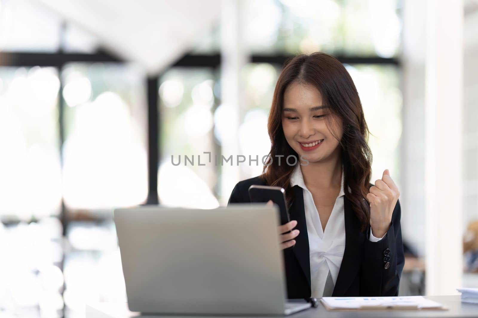 Successful and exciting businesswoman Young woman excited to win on her smartphone at work.