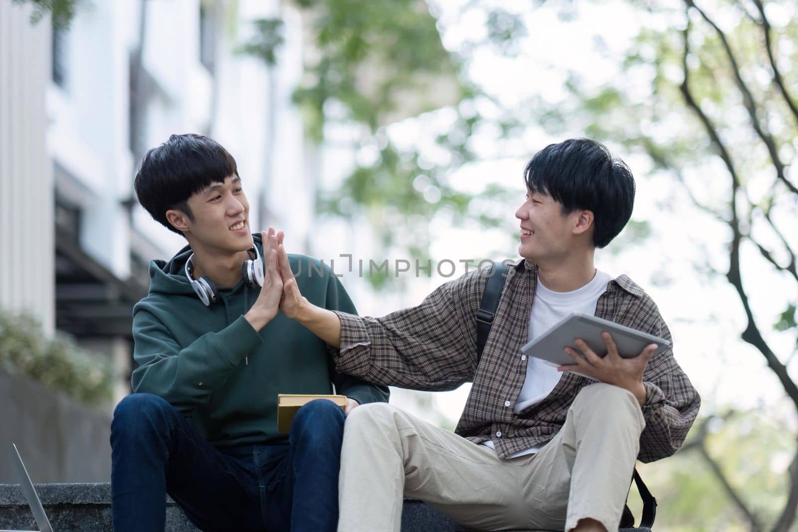 Two young Asian male college students discussing and working on their school project together.