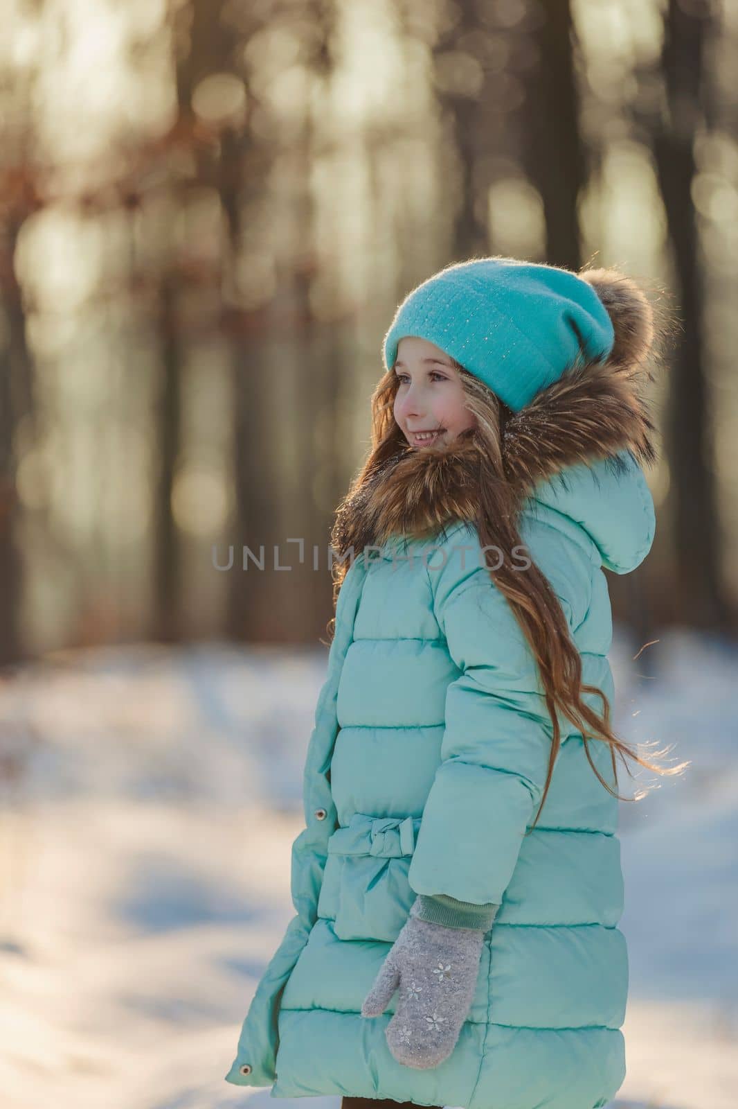 girl in a turquoise squat and a hat in a winter forest, shot vertically