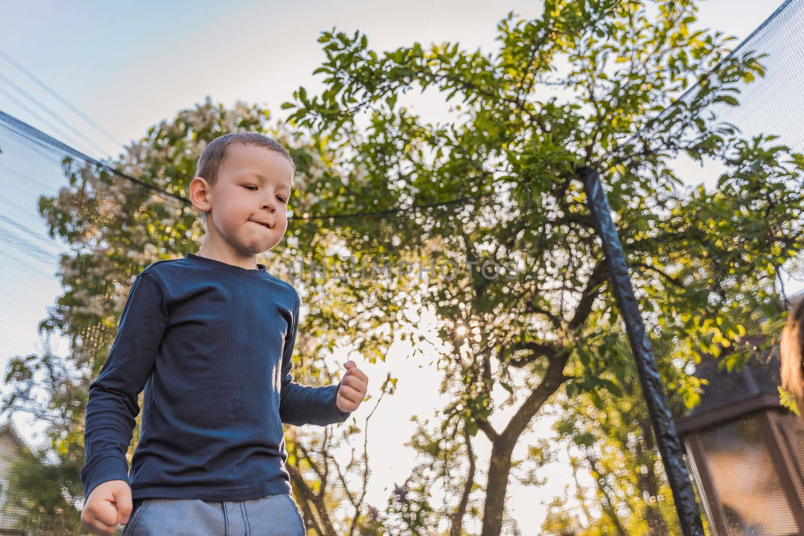 little boy jumps on a trampoline that stands in the yard