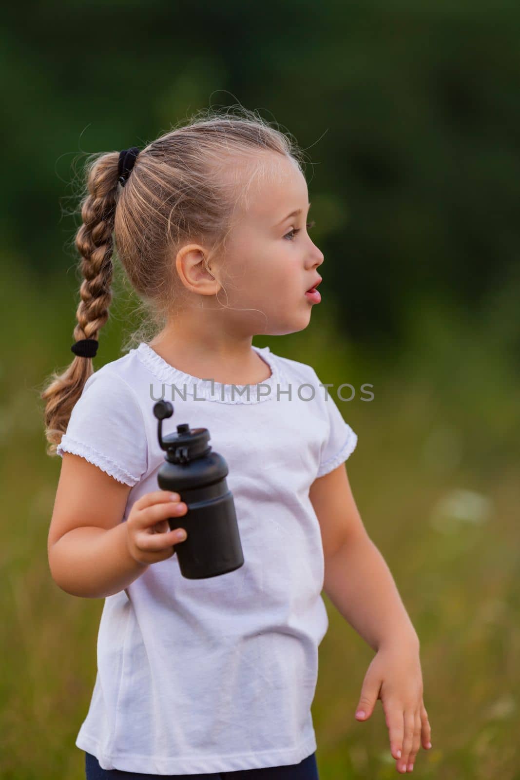 child drinking water from a bottle while outdoors