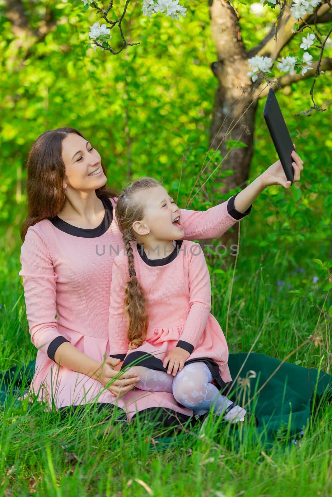 mother and daughter take pictures using a tablet in nature