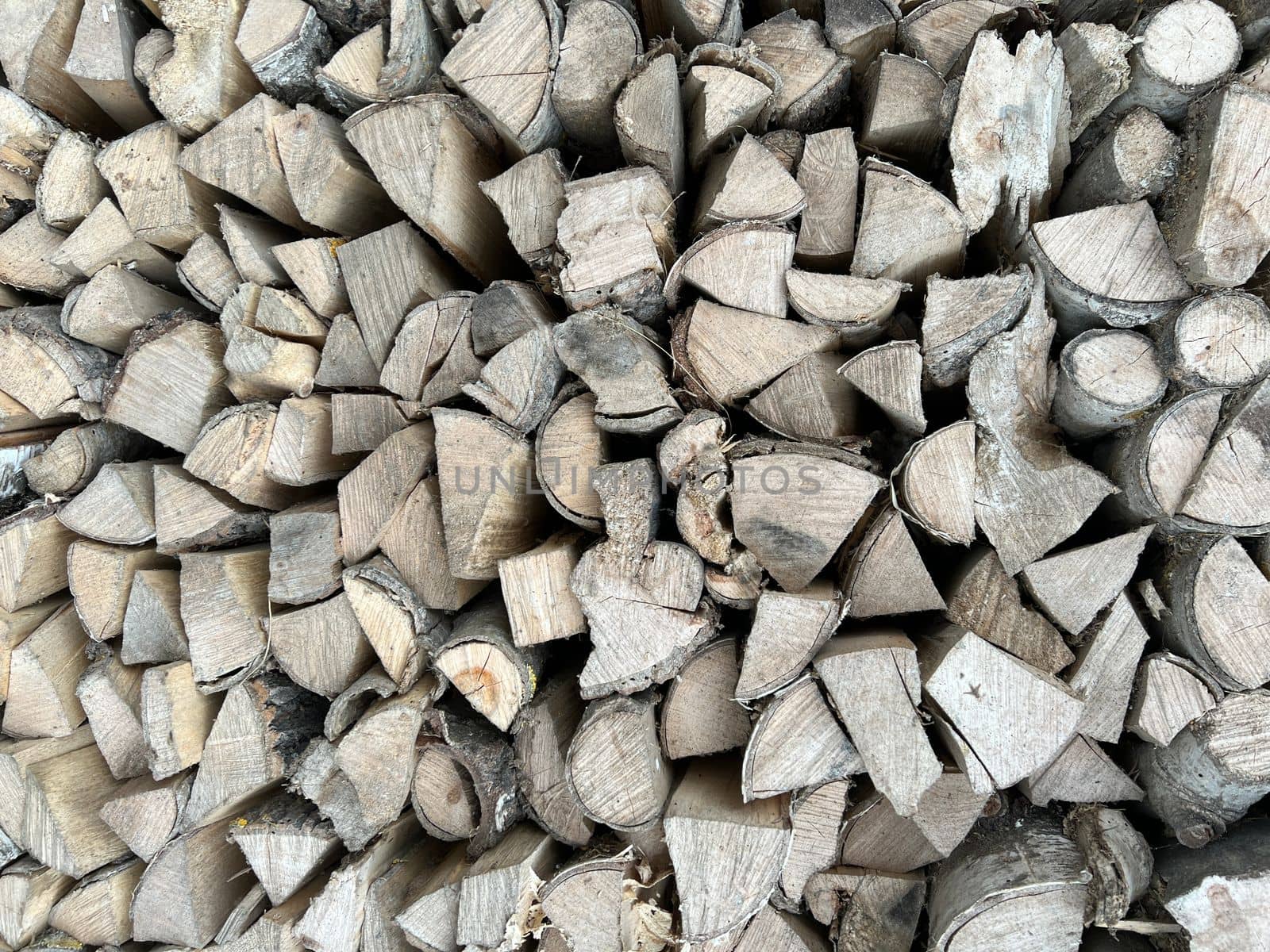 Natural wooden background - closeup of chopped firewood. Firewood stacked and prepared for winter. Wooden natural sawn logs as background