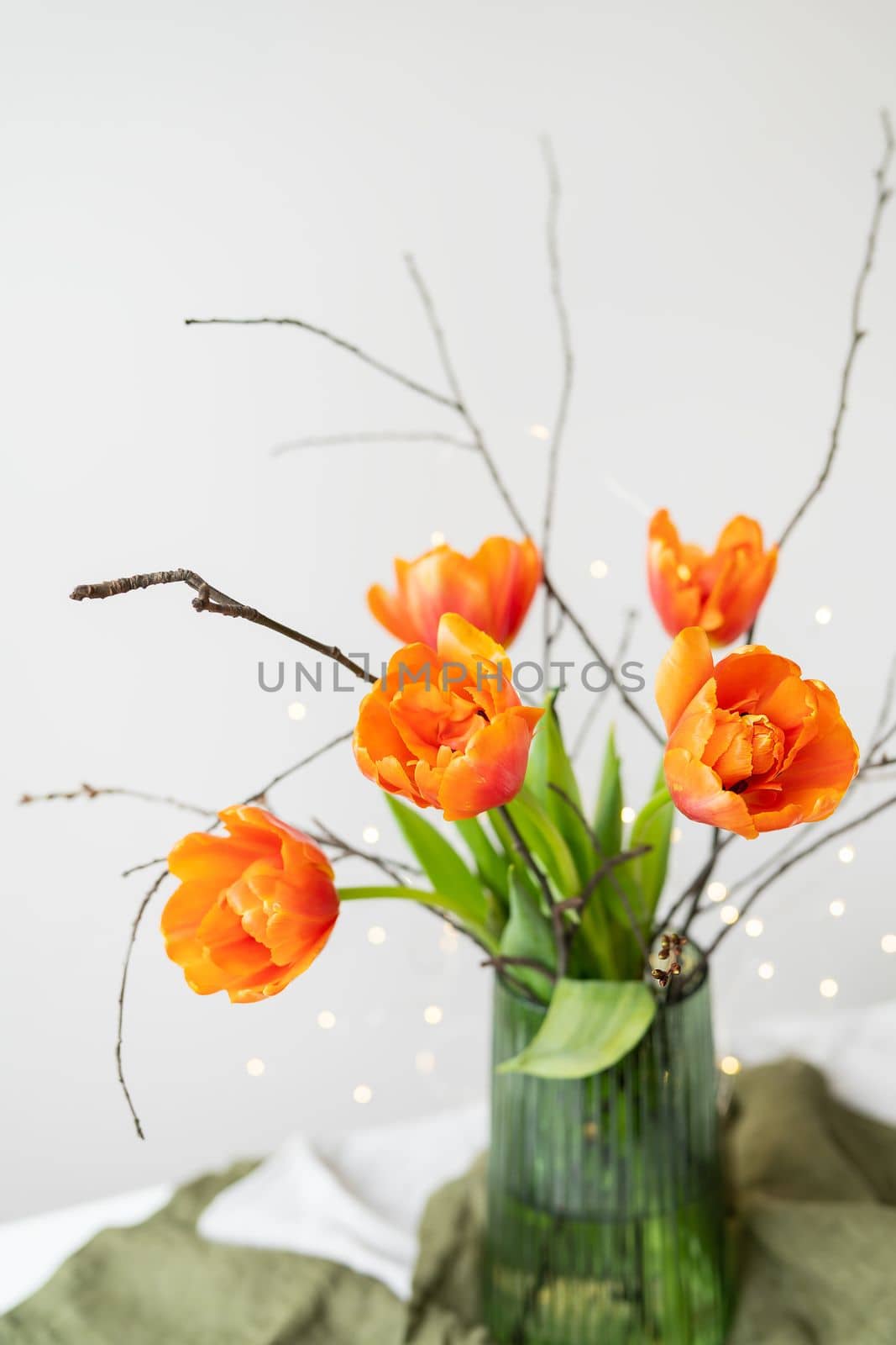 A very beautiful spring bouquet in a green vase stands on a table on a linen tablecloth, orange peony tulips. by sfinks