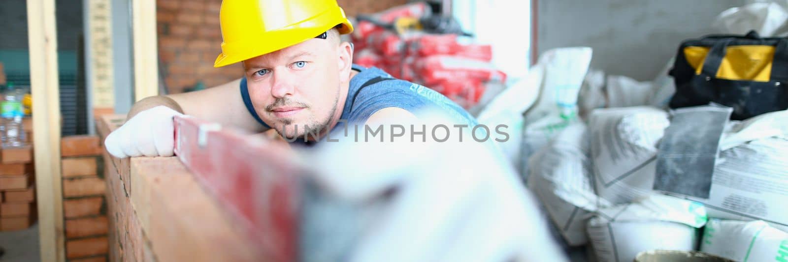 Builder carefully places red brick on masonry. Bricklayer work masonry construction wall concept