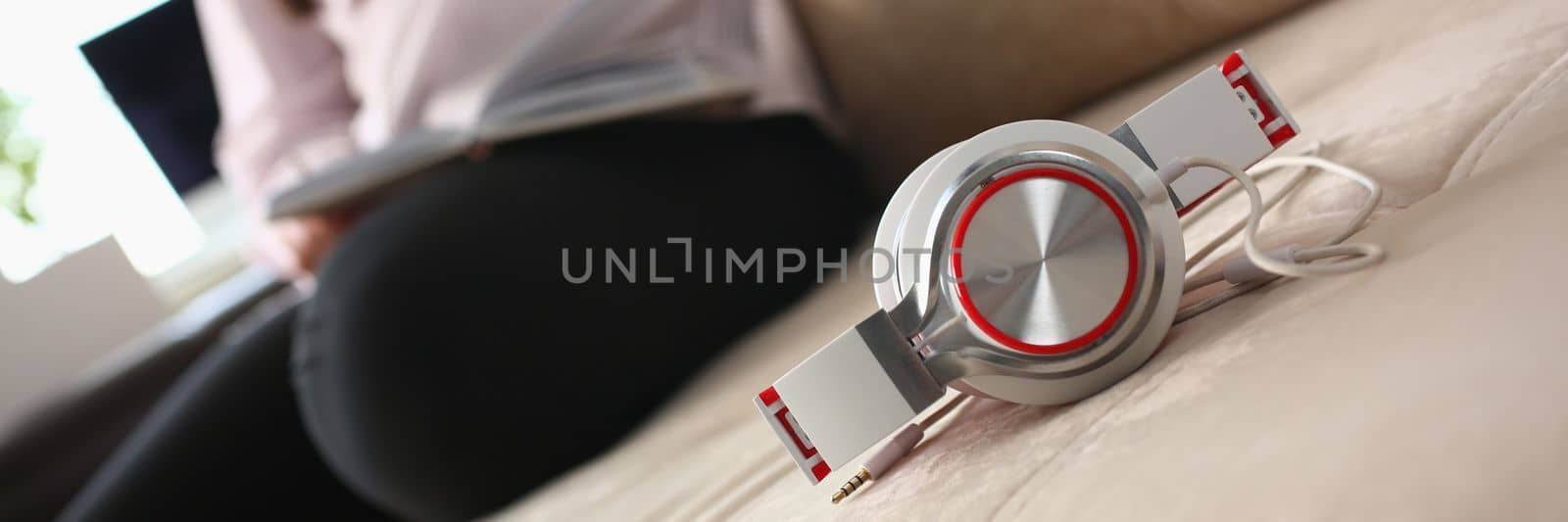 Fashionable white red headphones lie on the sofa in background person sits by kuprevich